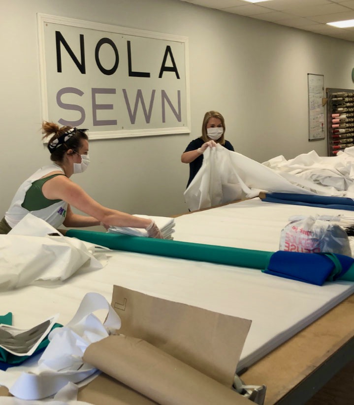 Two women in masks working with large pieces of fabric.